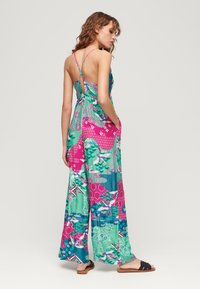 Vestido maxi multicolorido que presenta una mezcla de patrones verdes, rosas y azules; tirantes finos; corsé ajustado con lazo en la espalda y bolsillos.