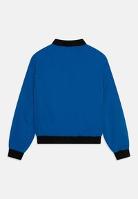 Niebieska kurtka typu bomber z czarnym prążkowanym kołnierzem i mankietami. Wykonana z gładkiego, lekkiego materiału, z elastycznym pasem dla wygody.