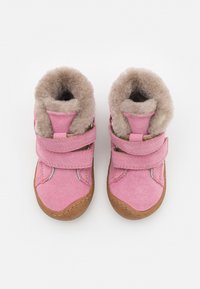 Bottes en daim rose avec doublure en fourrure, dotées de doubles bandes Velcro et d'une semelle en caoutchouc marron clair. Design à bout rond.