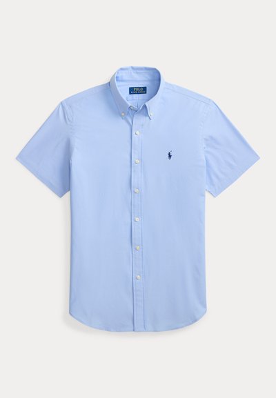 Chemise bleu clair à manches courtes avec col boutonné et petit logo foncé brodé sur la poitrine gauche.