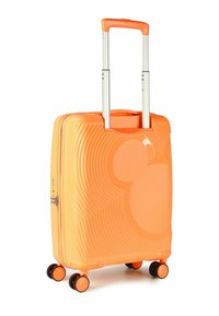 Valise rigide orange avec un design texturé, présentant une silhouette proéminente de Mickey Mouse, une poignée rétractable et quatre roues noires.