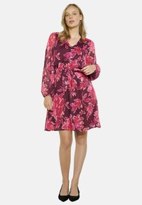 Vestido de manga corta en púrpura intenso con un gran patrón floral rosa, cintura ceñida y cierre de botones en la parte delantera. Textura sedosa y longitud hasta la rodilla.