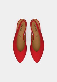 Κόκκινα σουέντ παπούτσια με λουράκι στο πίσω μέρος και μυτερή μύτη, με σχέδιο σε σχήμα V και μαλακή εσωτερική επένδυση. Το λογότυπο της μάρκας είναι ορατό στις εσωτερικές σόλες.