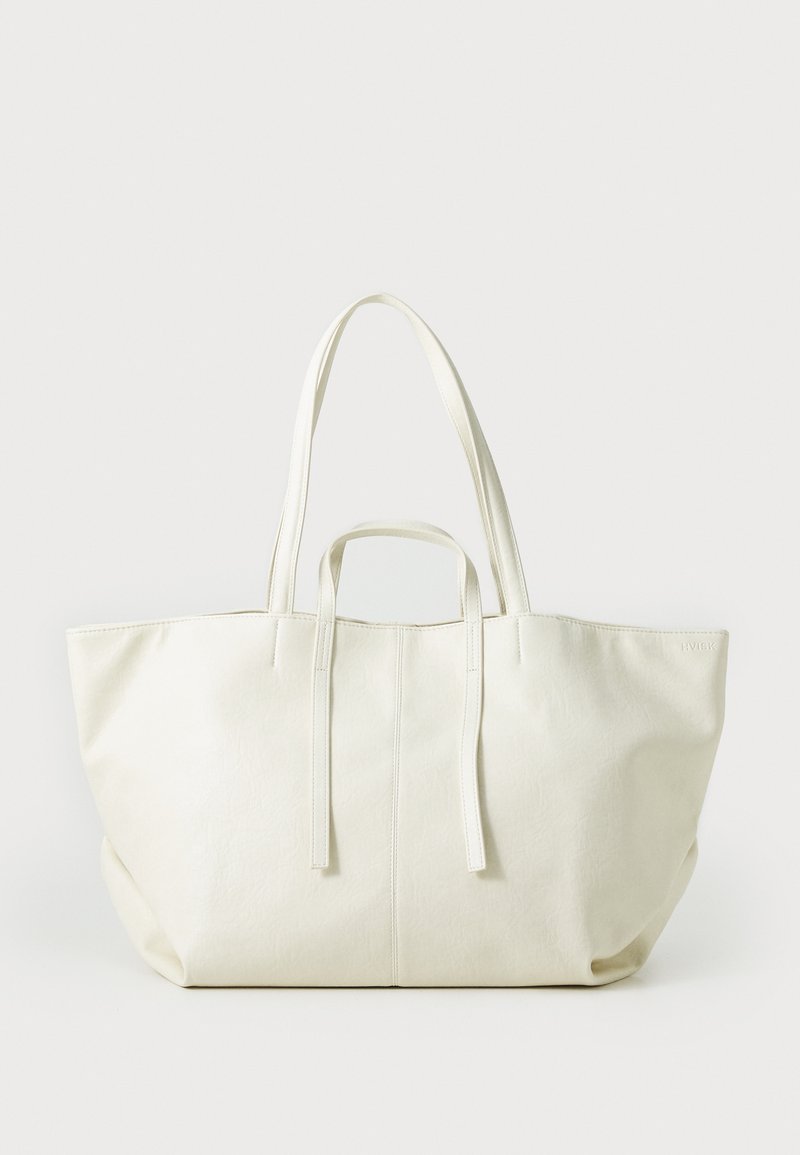 Large, white tote bag made of textured synthetic material, featuring two long handles, open top, and minimalistic design.