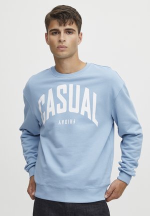 Sudadera azul claro hecha de tela suave, con un atrevido texto blanco "VIERNES CASUAL", cuellos y dobladillos acanalados, y un diseño de cuello redondo.