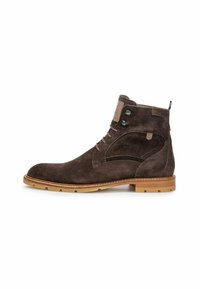 Stivaletto alla caviglia in suede marrone scuro con lacci frontali, occhielli in metallo, suola cucita color beige e linguetta sul retro.