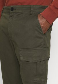 Cargo-byxor i olivgrön, med rak passform, sidofickor och en texturerad tyg. Inkluderar en knappstängning i midjan.