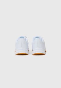 Des chaussures de sport blanches avec une tige lisse, un col rembourré et une semelle extérieure en caoutchouc naturel. Elles présentent un design minimaliste et des accents perforés.