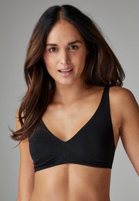 Svart kort bralette med V-ringning, tillverkad av mjukt tyg. Har breda band och en sömlös framdel med en slät yta.