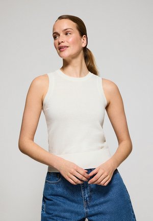 Sleeveless white knit top with a fitted design, ribbed collar and hem, paired with blue high-waisted denim jeans. Simple and clean appearance.