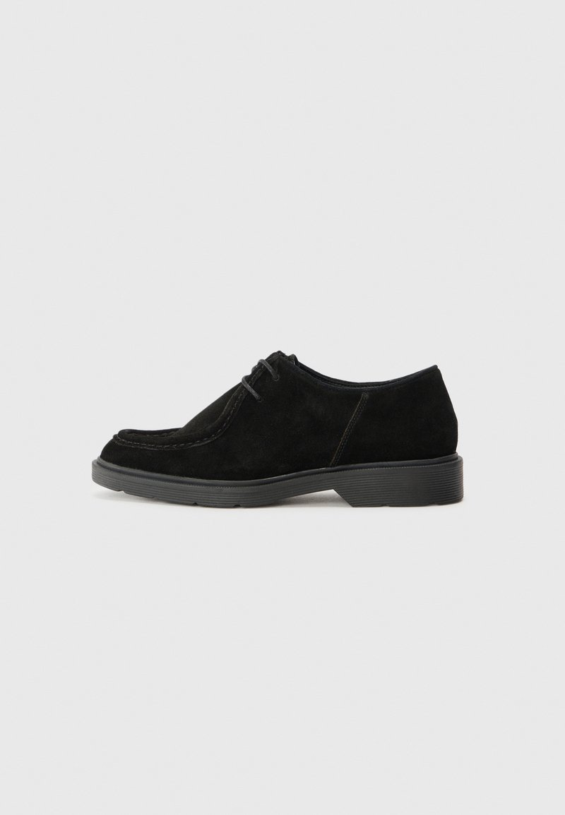 Chaussure habillée en suède noir avec un bout arrondi, des coutures contrastées et une semelle en caoutchouc. Présente un laçage minimal et un design supérieur lisse.