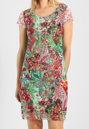 Frau trägt ein kurzärmeliges, knielanges Kleid mit einem lebhaften Blumen- und Blättermuster in Rot-, Grün- und Pinktönen.