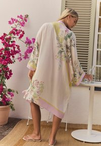 Svetlo cvetli kimono v pastelnih barvah, z obsežnimi rokavi in dolžino do kolen. Narejen iz mehkega blaga z gladko teksturo.