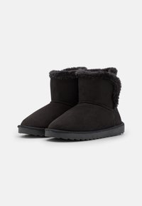 Un par de botas de tobillo de ante negro con forro de suave piel sintética y suelas de goma, diseñadas para mantener el calor y el uso casual.