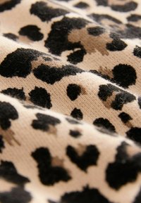 Kangas kuviollinen leopardi, jossa on vaalea beige tausta ja voimakkaat mustat pilkut. Tekstuuri näyttää pehmeältä, ja siinä näkyy kudontayksityiskohtia.