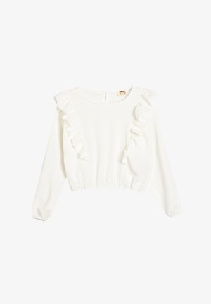 White long-sleeve blouse with ruffled accents along the shoulders and a fitted waistband. Textured fabric with a scoop neckline and back closure.