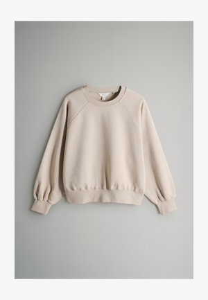 Beige sweatshirt med ribbede rund halsudskæring, raglanærmer og elastiske manchetter. Blødt stof med let stræk, ingen synlige mønstre eller hardware.