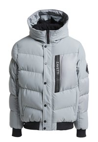 Veste matelassée gris clair avec un col haut, des accents noirs, une fermeture éclaire sur le devant et des boutons pression. Présente un motif matelassé horizontal.
