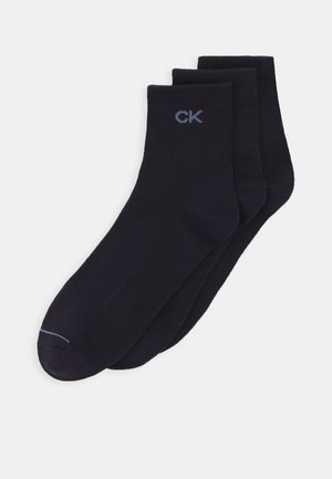 Three pairs of navy blue cotton socks with a smooth texture and light blue "CK" logo on the ankle, featuring a ribbed cuff design.