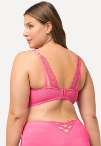 Roze lingerieset met een bh met kantaccenten, verstelbare banden en een haaksluiting, en bijpassende slip met een kruisdetaillering aan de achterkant.
