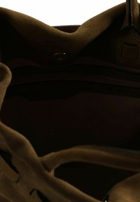 Interno di borsa in camoscio verde oliva con una superficie liscia, dotato di tasca con cerniera e chiusura a scatto magnetico. Design minimale con fodera scura.