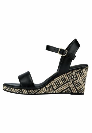 Czarna skórzana sandałka na koturnie z szerokim paskiem z przodu, paskiem wokół kostki i detalem z klamrą. Wzorzysta koturna prezentuje geometryczny wzór w odcieniach beżu i czerni.