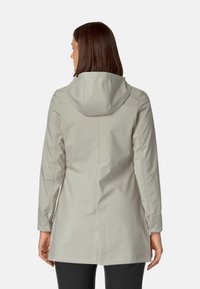 Jasnoszary płaszcz z kapturem o gładkiej, wodoodpornej tkaninie, o długości średniej, z subtelnymi detalami przeszycia na plecach i rękawach.