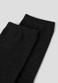 Juodos kojinės iš minkšto, tekstūruoto mezginio audinio. Jos turi ribuotu viršumi ir paprastą, be siūlių dizainą.