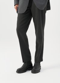 Melni Chelsea zābaki ar bieziem gumijas zole, valkāti ar antracīta pelēku bokseru biksēm ar smalkām svītrām un gludu tekstūru.