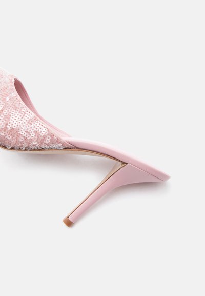 Ροζ mule με ψηλό τακούνι και μυτερή μύτη, καλυμμένο με λαμπερά παγιέτες, φωτογραφημένο σε λευκό φόντο.