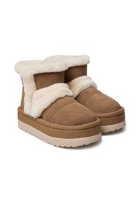 Braune Wildleder-Winterstiefel mit dicken beigefarbenen Gummisohlen und weichem, cremefarbenem Fleece-Futter, das an den Bündchen und den vorderen Riemen sichtbar ist.