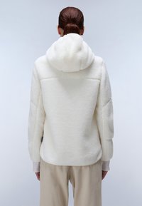 Witte fleecejacket met capuchon, met een gestructureerd oppervlak en een ontspannen pasvorm. Kenmerkt zich door een drop shoulder en een naadloos ontwerp aan de achterkant.