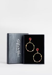 Orecchini a cerchio dorati in una scatola regalo, con accenti a goccia rossa e pietre circolari colorate, poggianti su un inserto in velluto nero.