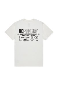 Biała koszulka z krótkim rękawem z czarnym tekstem i logo na plecach, na którym znajdują się napisy "DC SHOE CO", "Produkt wykonany na zamówienie" oraz różne symbole graficzne i etykiety.