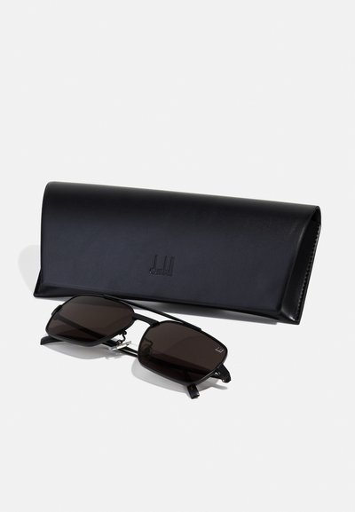 Occhiali da sole con lenti scure e montatura in metallo angolare, accompagnati da una custodia in pelle nera con logo in rilievo e superficie liscia.