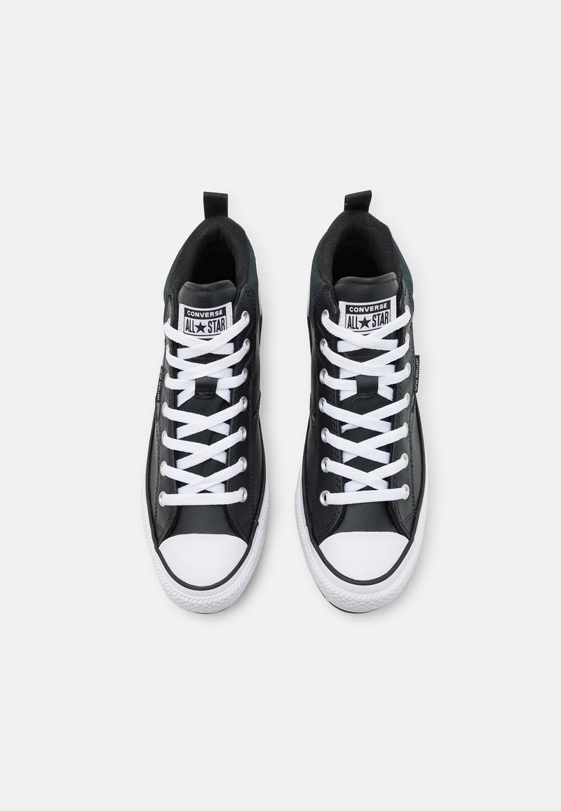 Sorte høje sneakers med hvide snørebånd og gummitåhætte. Har et mærke med "Converse All Star" logo på tungen og en glat lædertekstur.