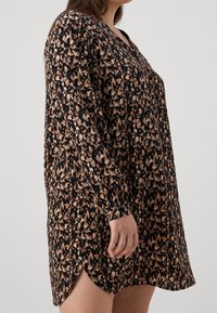 Abito nero con maniche lunghe e scollatura a V, caratterizzato da un motivo astratto in tonalità beige e marrone, materiale morbido e alte spaccature laterali.