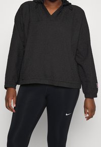 Zwarte pullover hoodie van een gestructureerde stof, met een v-hals, een verstelbare trekkoordcapuchon en lange mouwen. Gecombineerd met zwarte leggings met een logo.