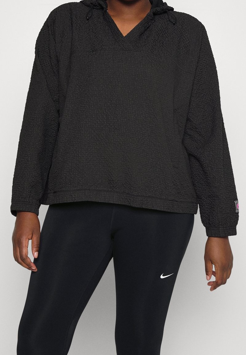 Zwarte pullover hoodie van een gestructureerde stof, met een v-hals, een verstelbare trekkoordcapuchon en lange mouwen. Gecombineerd met zwarte leggings met een logo.