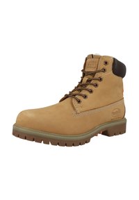 Bota tobillo de ante en tono tan con detalles en cuero marrón, suela resistente, ojales metálicos y costuras en contraste. Cuenta con un cuello acolchado para mayor comodidad.