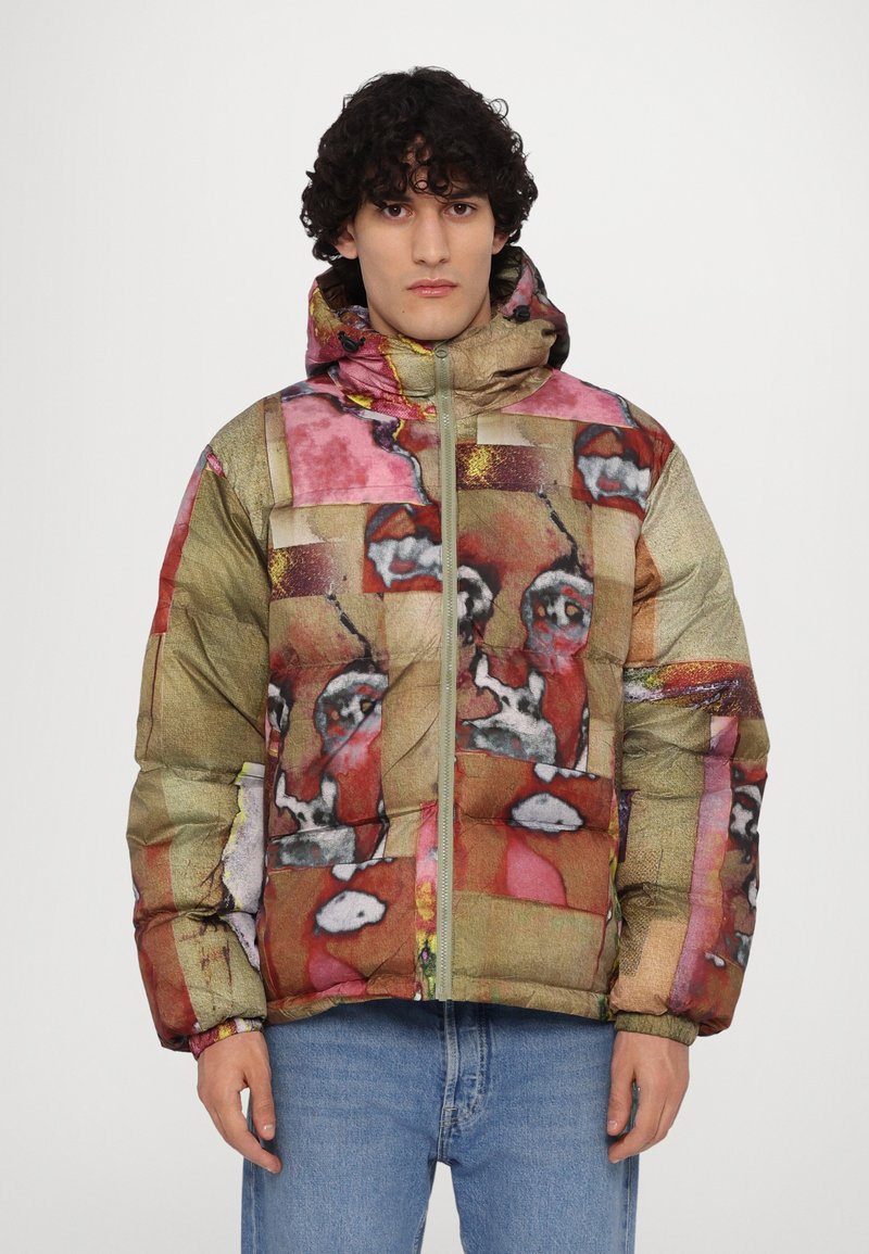Puffer jacket in mixed colors with an abstract, patchwork design. Features a high collar, front zipper, and elastic cuffs. Textured fabric.