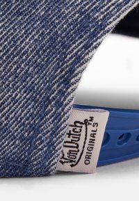 Denim kapa z modro osnovo, ki ima teksturirano tkanino temno modre barve z belimi črtami in oznako, ki prikazuje "Von Dutch Originals."