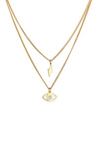 Collier en plusieurs couches dorées mettant en avant un pendentif en forme d'éclair et un œil avec un strass central, sur des maillons de chaîne fine.