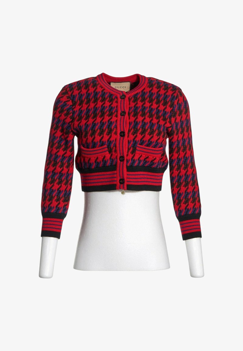 Cardigan court à motif pied-de-poule rouge, noir et bleu avec boutons noirs, manches longues et deux poches avant sur un torse de mannequin blanc.