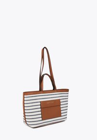 Bruna läderremmar kompletterar en rektangulär toteväska med blå och vita horisontella ränder, med en framficka och logodetalj.