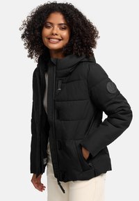 Black padded jacket with a detachable hood, featuring a zippered front, textured fabric, and a logo patch on the sleeve.