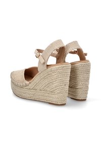 Sandalias de cuña de esparto beige con suela de yute trenzado, que cuentan con una correa en el tobillo estampada y punta redonda. Material superior de ante suave.