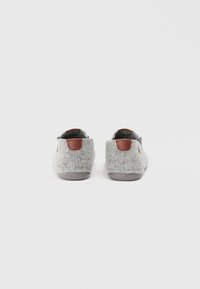 Chaussons gris en feutre avec une semelle synthétique, ornés d'un accent en cuir marron au talon et d'un design simple sans motifs supplémentaires.