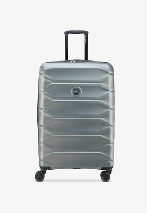 Valise rigide argentée avec quatre roues et une poignée rétractable noire étendue, vue de face sur fond blanc.