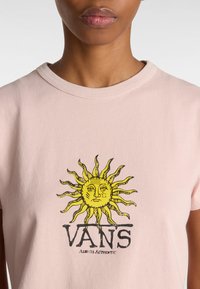 Růžové bavlněné tričko s grafikou žlutého slunce s obličejem a černým textem "VANS" pod ním. Klasický design s kulatým výstřihem.